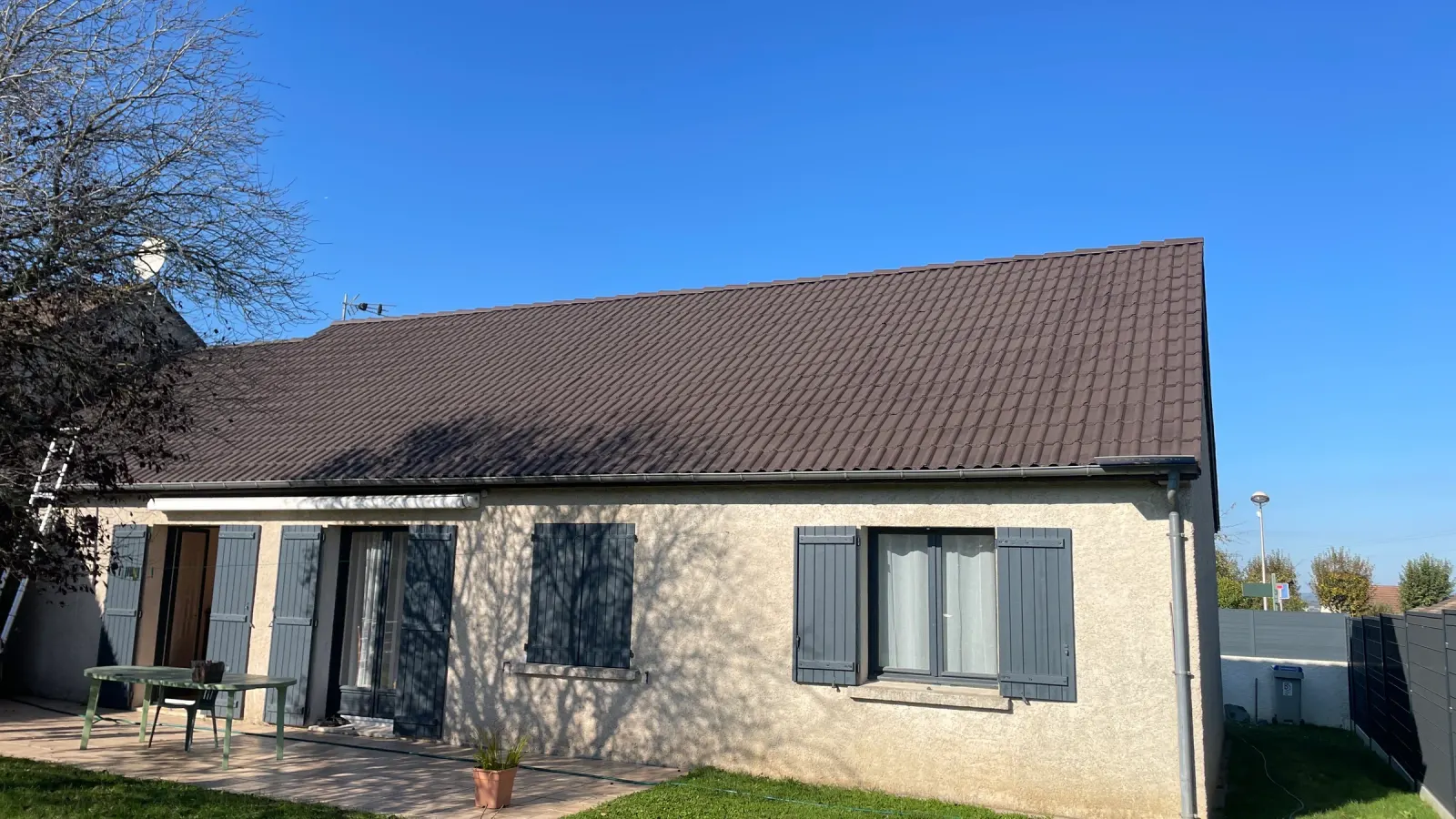 Maison avec toiture en tuiles rénovée, ciel bleu dégagé